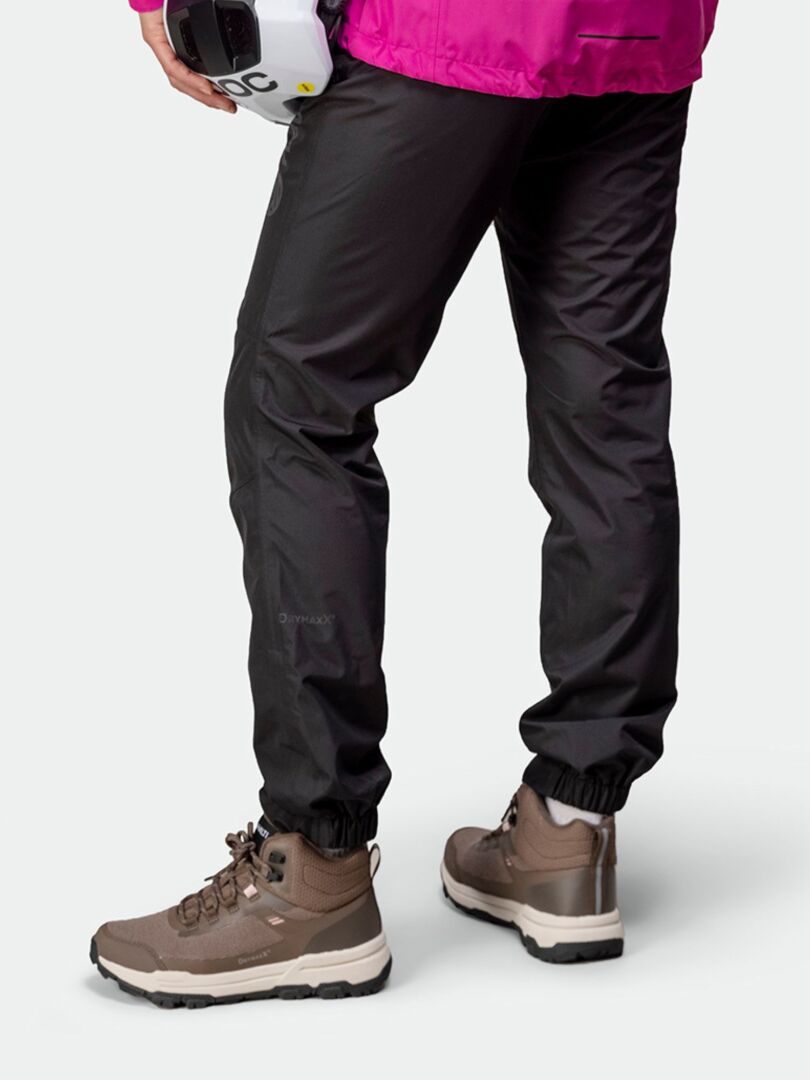 Eine Person in schwarzer Hose und Halti Fara 3 DX Mid Outdoor Schuhe Damen hält einen weißen Helm, von hinten fotografiert.