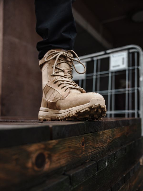 Eine Person in Halti Regis DX Stiefel Herren steht auf einer Holzplattform an einem Metallzaun.