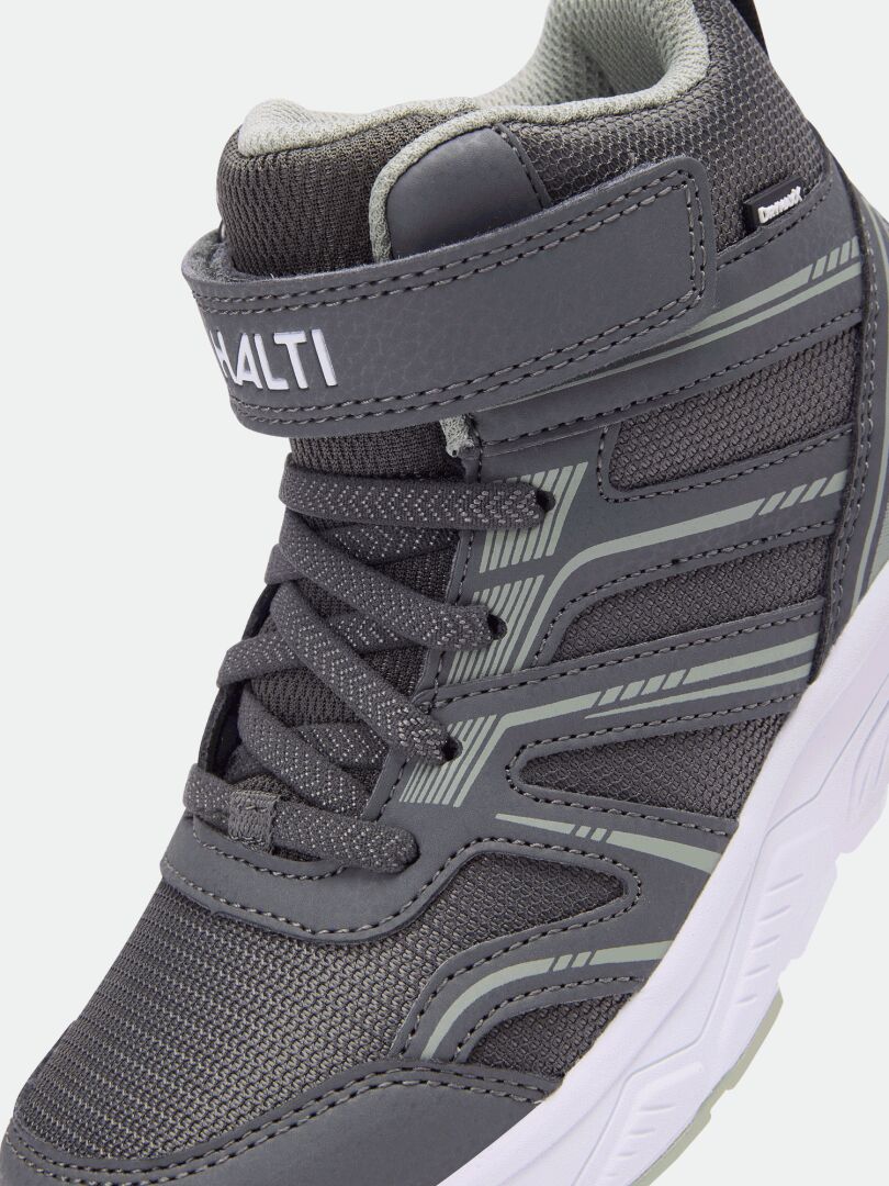Nahaufnahme des Halti Zuma Mid DX Sneakers für Kinder mit Schnürung, Klettverschluss und weißer Sohle vor hellem Hintergrund.