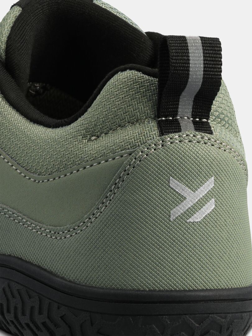 Nahaufnahme des „Tuntuma DX Barfußschuh Damen“ von Halti, zu sehen sind eine schwarze Zuglasche und ein silbernes geometrisches Logo an der Ferse.