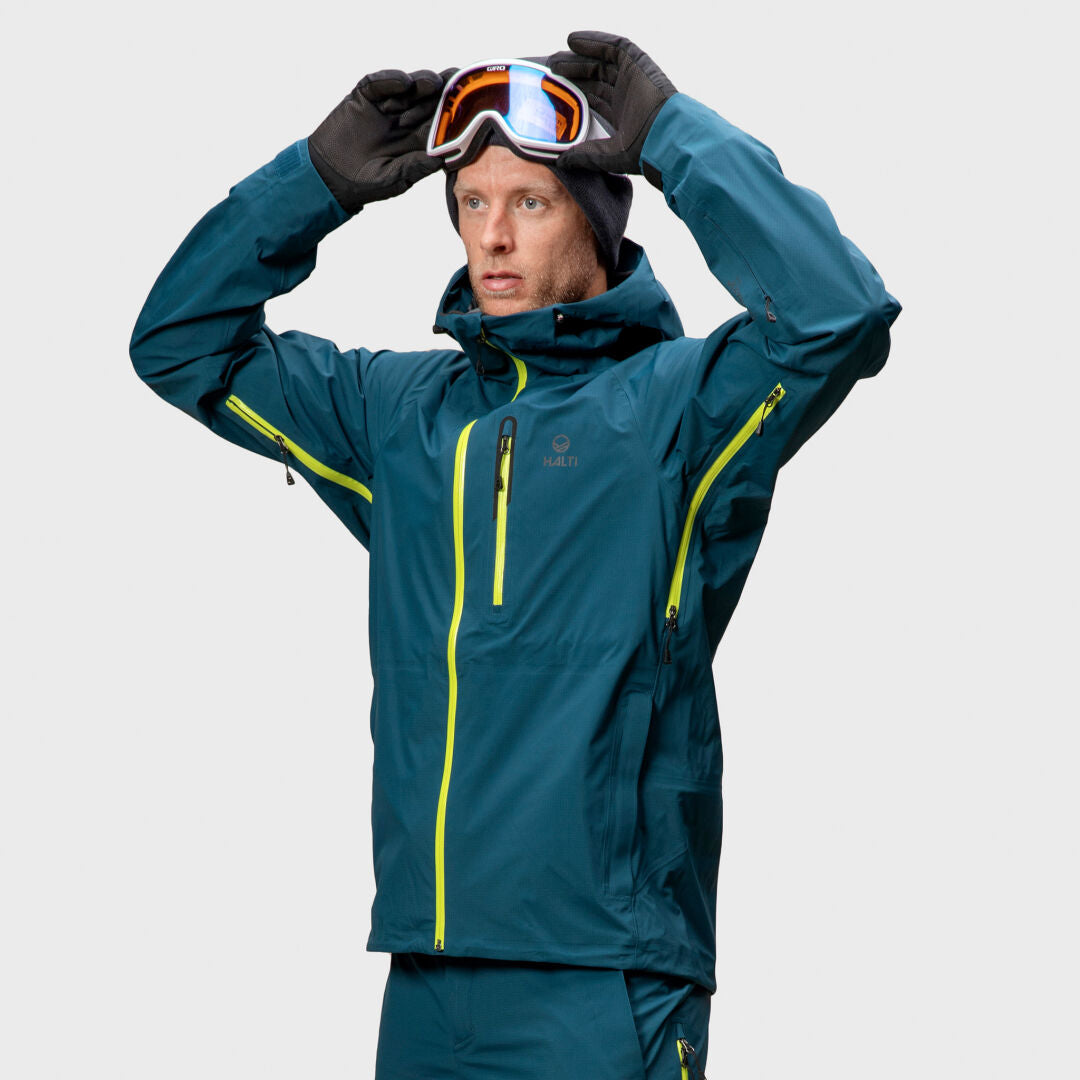 Person in Halti Alpine 3L DX Skijacke Unisex und Handschuhen passt Skibrille an - ideal für Backcountry-Ski.