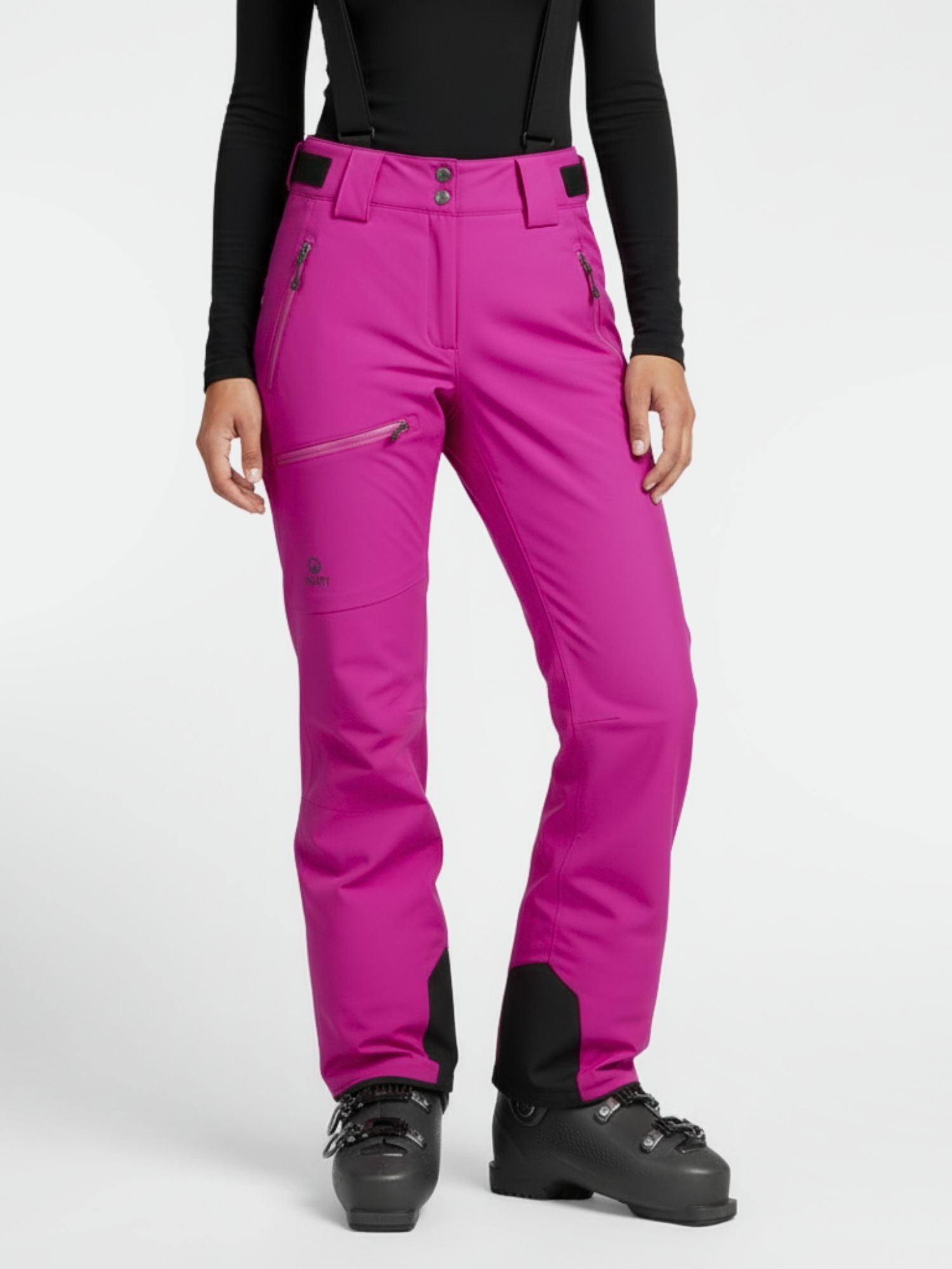 Person trägt Halti Carvey DX Skihose Damen in Magenta, schwarzes langärmeliges Oberteil und Skischuhe auf weißem Hintergrund.