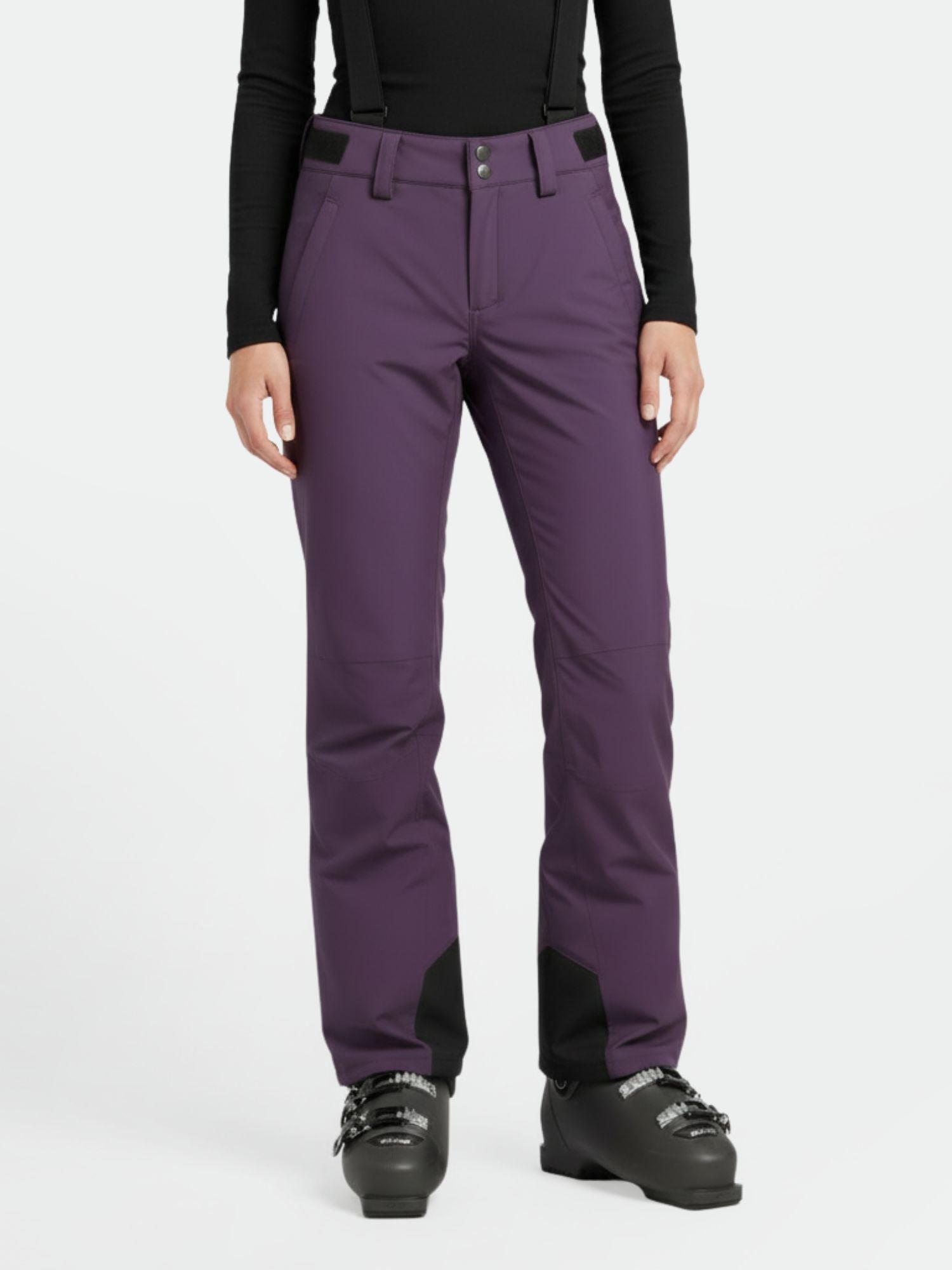 Eine Person in lila Halti Trusty DrymaxX Skihose Damen, schwarzen Hosenträgern, schwarzem Top und Skischuhen auf weißem Hintergrund.