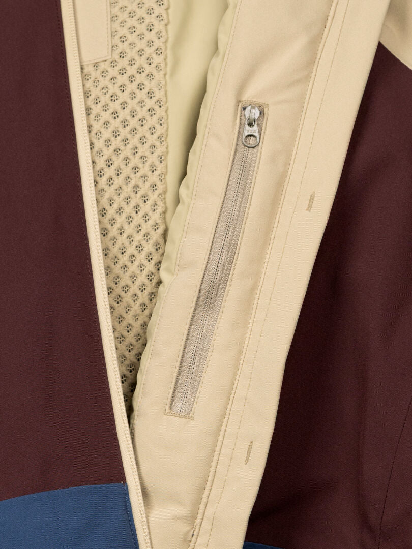 Nahaufnahme der Halti Gracer DX Skijacke Damen mit beiger Reißverschlusstasche, Netzfutter und braunen, beigen und blauen Einsätzen.