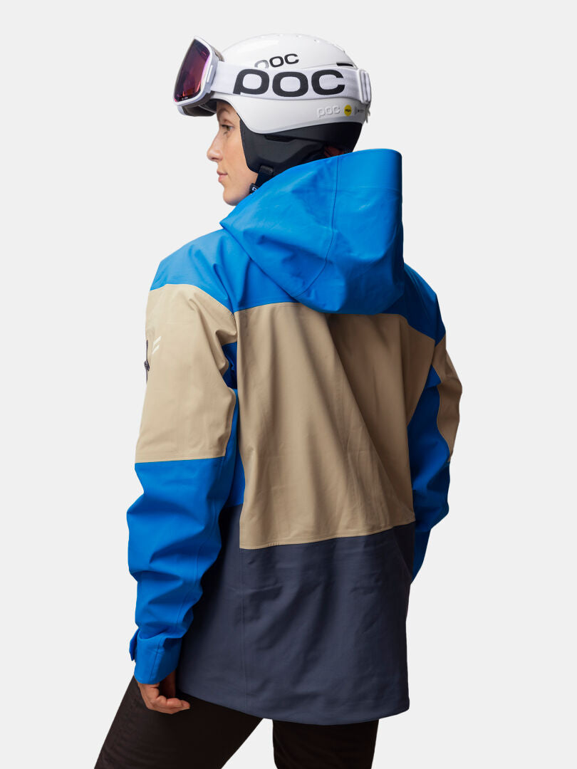 Diese Person trägt eine Halti Rizle Unisex 3L DX Skijacke, einen weißen Helm und eine Skibrille und schaut von der Kamera weg.