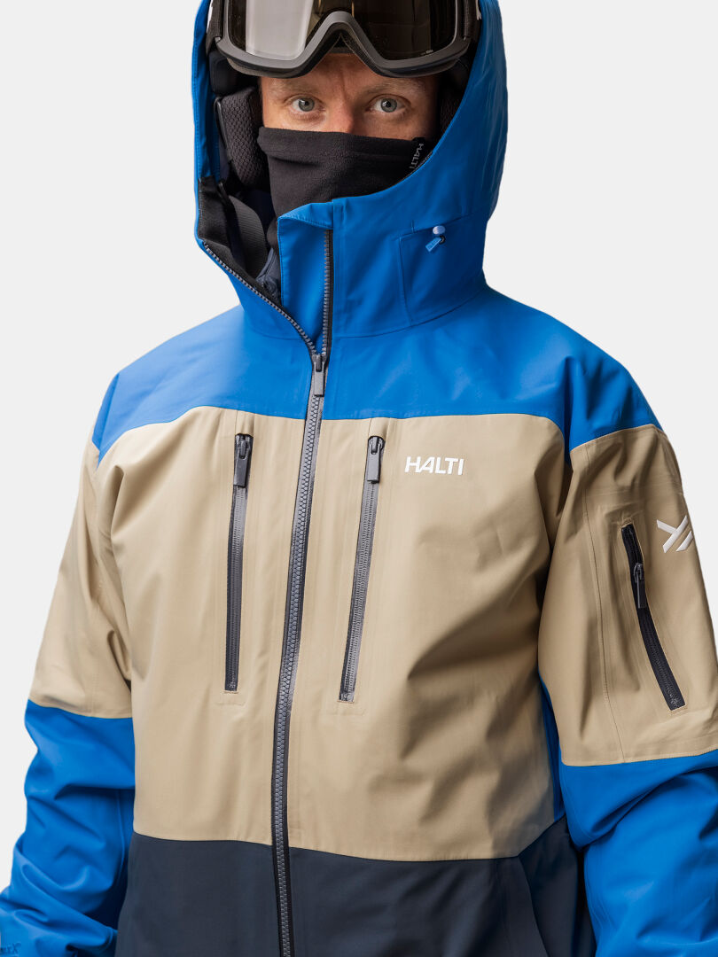 Person in einer Halti Rizle Unisex 3L DX Skijacke mit Primaloft Fleece, Kapuze, Schutzbrille und Gesichtsschutz.