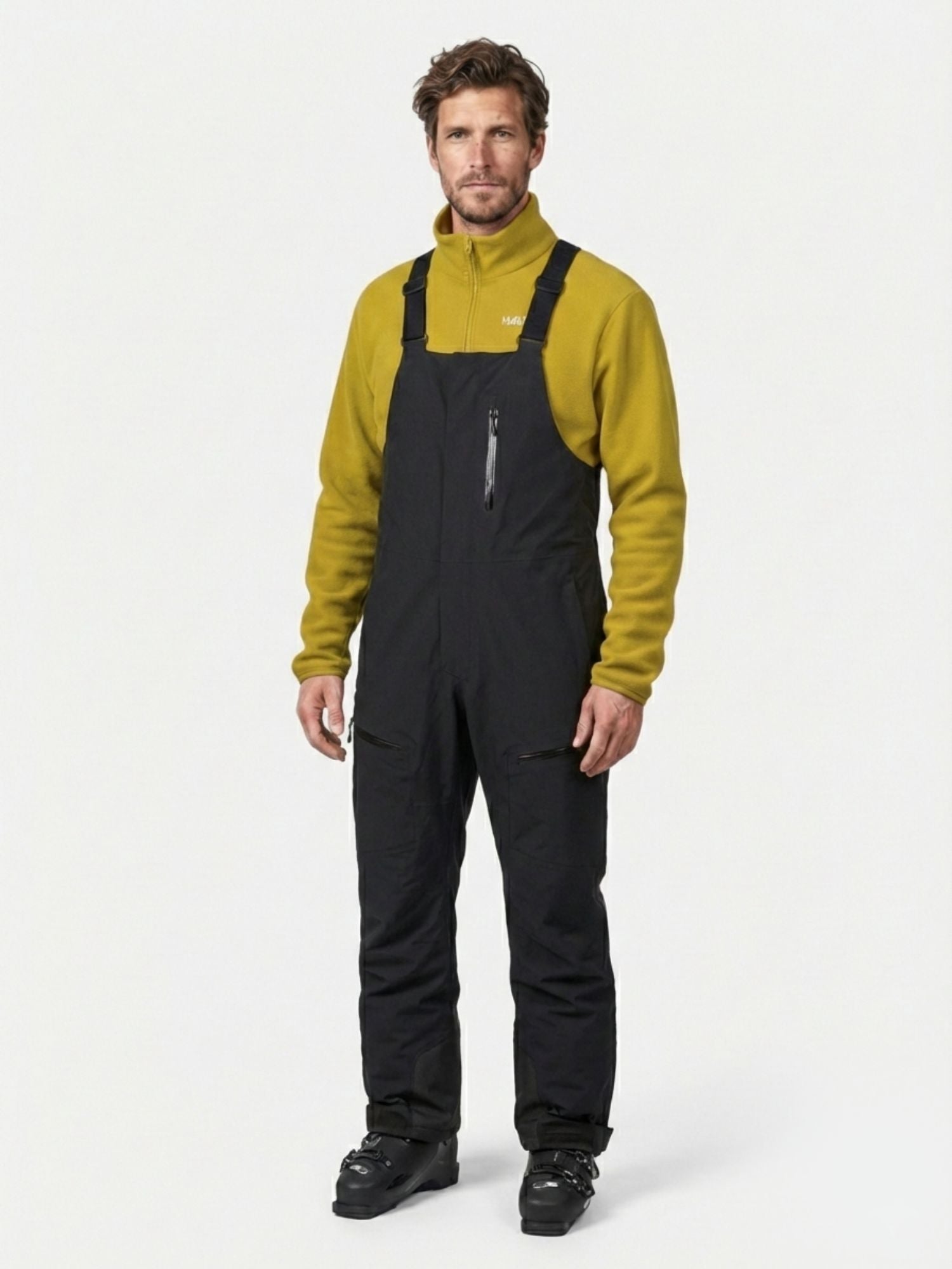 Mann in gelber Fleecejacke mit Reißverschluss und Halti Rizle 3L DX Skihose Unisex, stehend auf einem schlichten weißen Hintergrund.