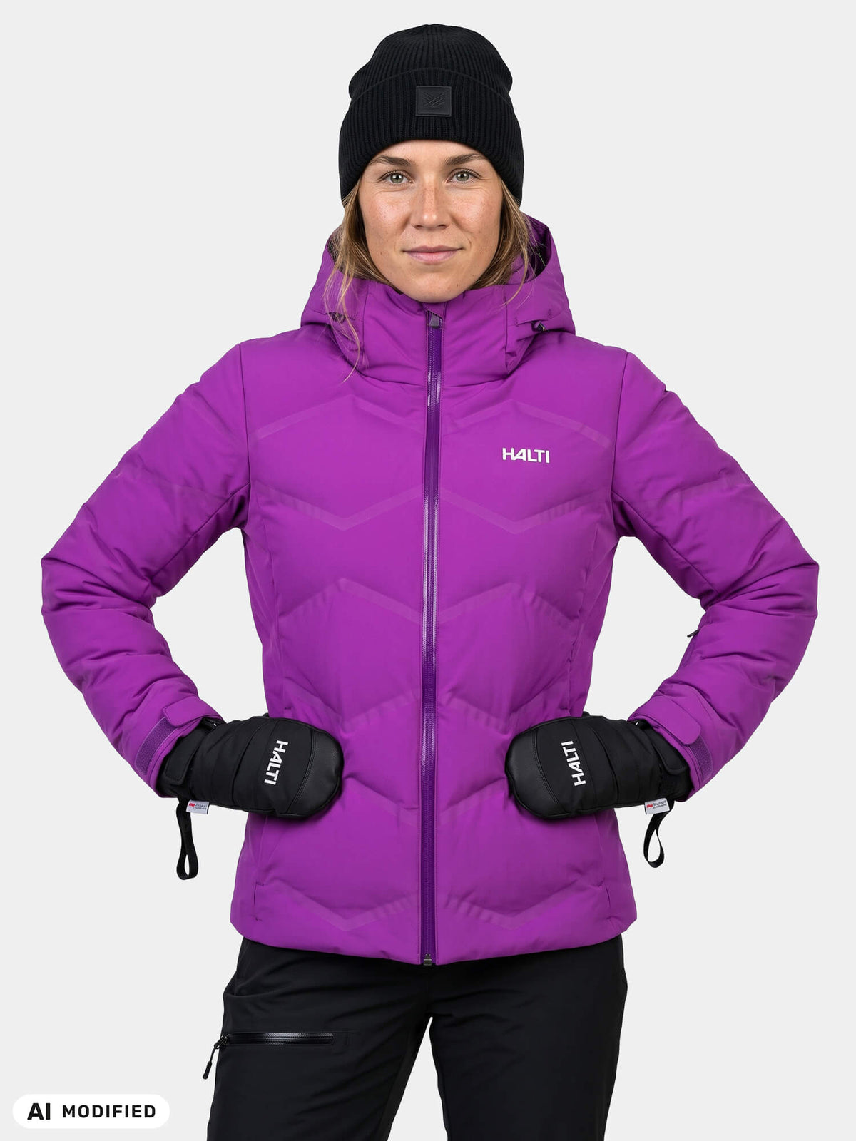 Eine Person, die eine lila Halti Nordic Arcty II Skijacke Damen, eine schwarze Mütze und schwarze Fäustlinge trägt.
