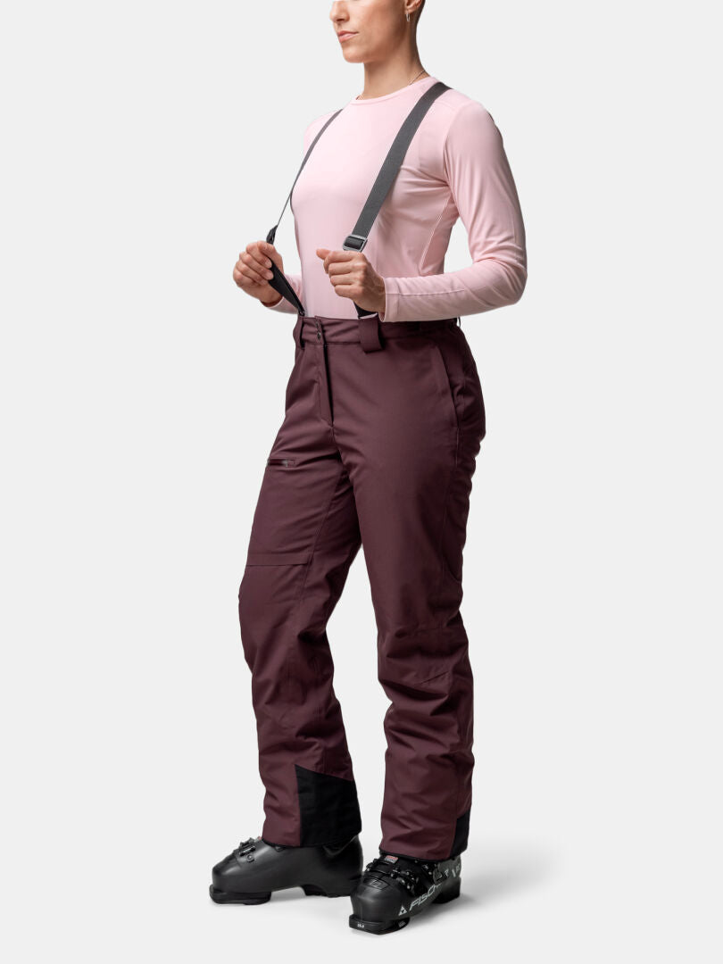 Person, die ein hellrosa Hemd, Halti Carvey II DX Damen Skihose mit Hosenträgern und schwarze Skistiefel trägt, aufrecht stehend.