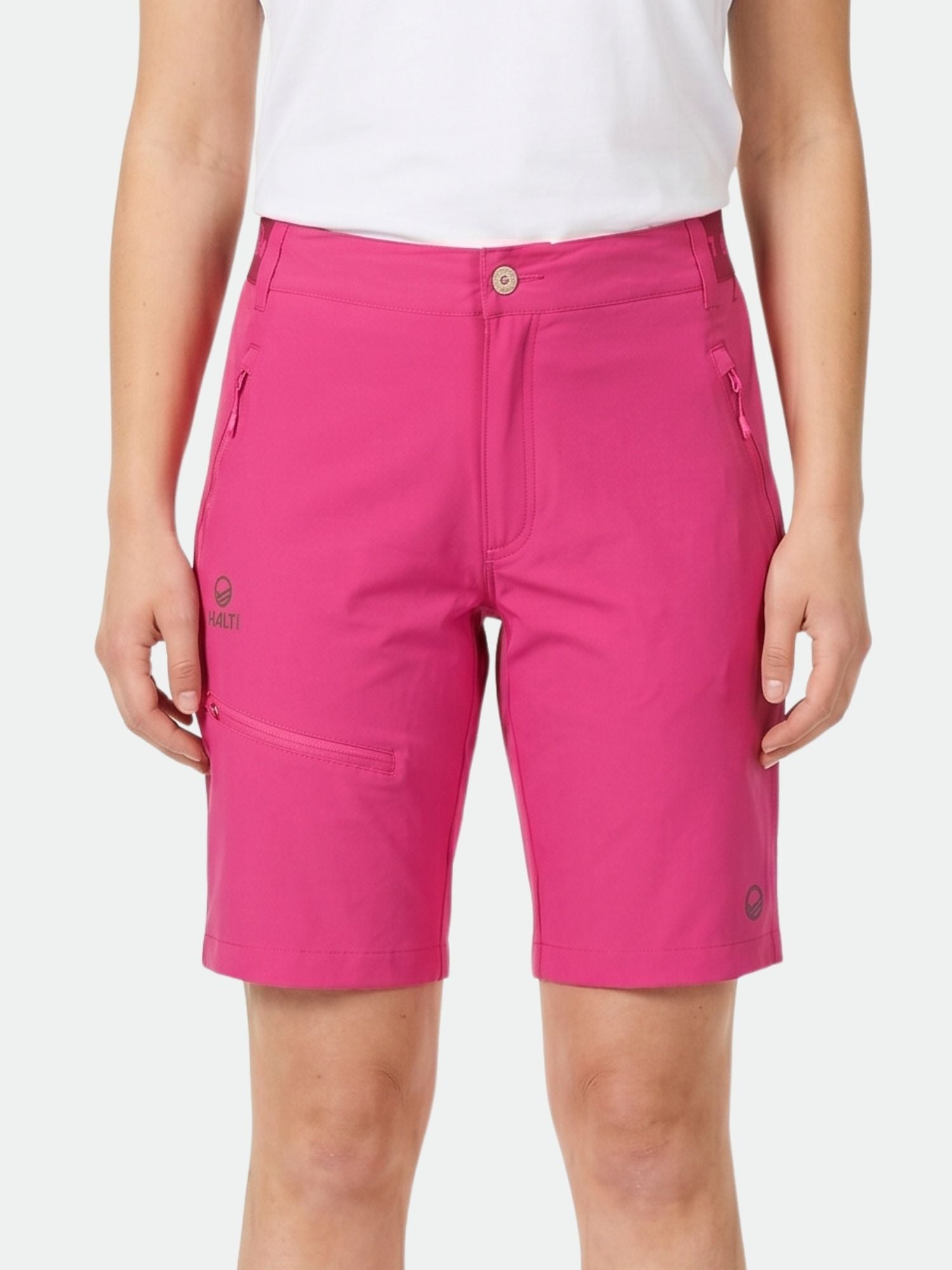 Die Person trägt hellrosa Halti Pallas Damen X-stretch Lite Shorts mit Reißverschlusstaschen und ein weißes Hemd, ideal für draußen.