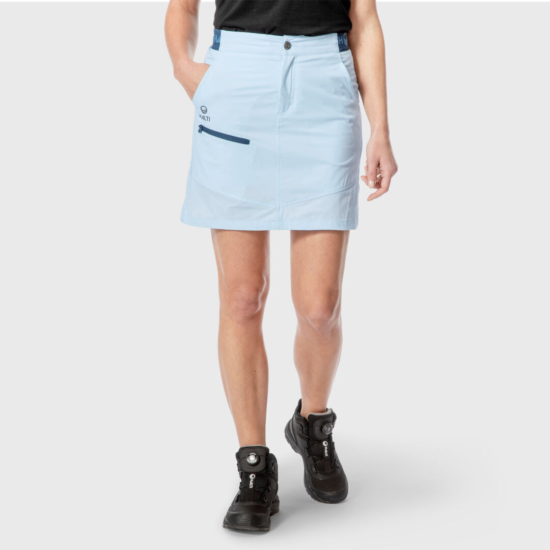 Person trägt den Pallas Damen Lite X-stretch Rock von Halti in Hellblau, schwarzes Shirt und Wanderschuhe - ideal für draußen.