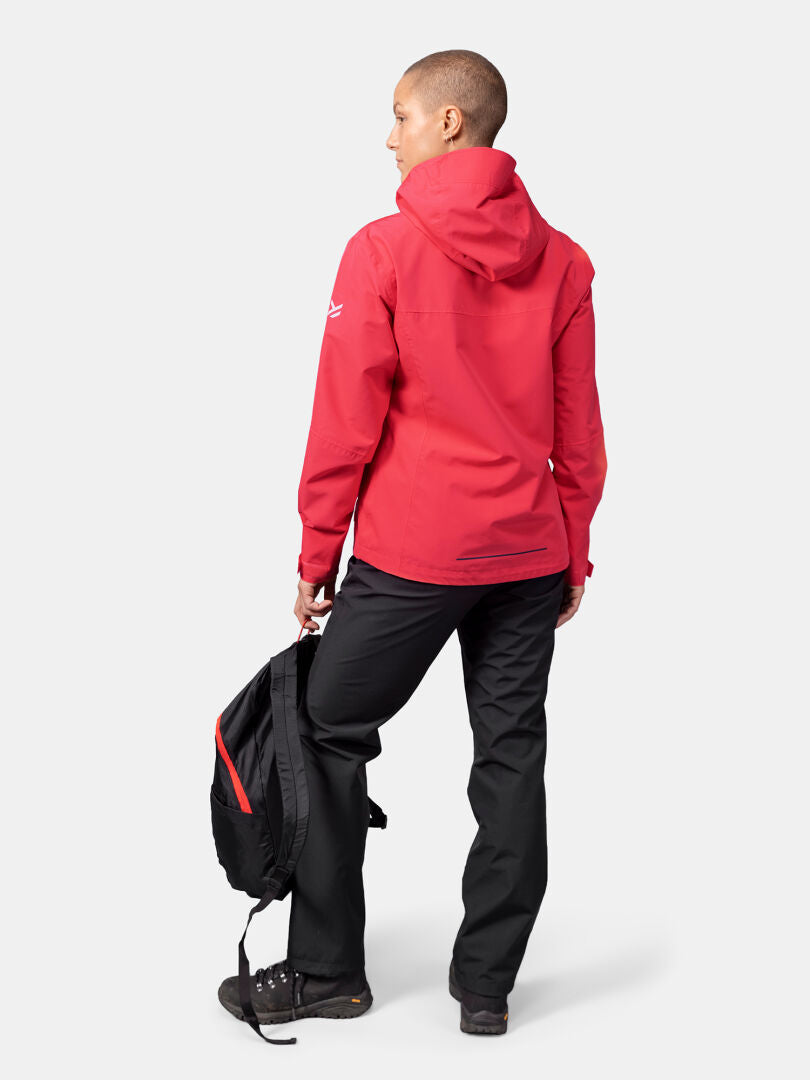 Die Person trägt eine Halti Forter DX Regenjacke Damen, eine schwarze Hose und hält einen schwarzen Rucksack mit dem Rücken zur Kamera.