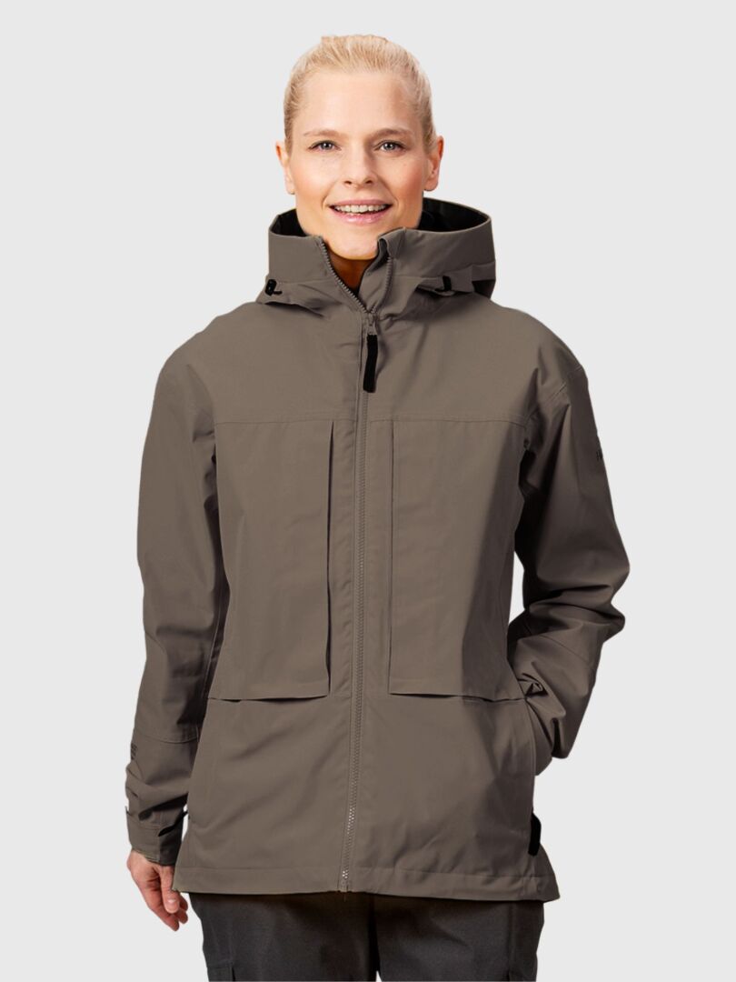 Eine Frau in einer taupefarbenen Halti Hiker II DX Regenjacke steht vor einem schlichten hellgrauen Hintergrund.