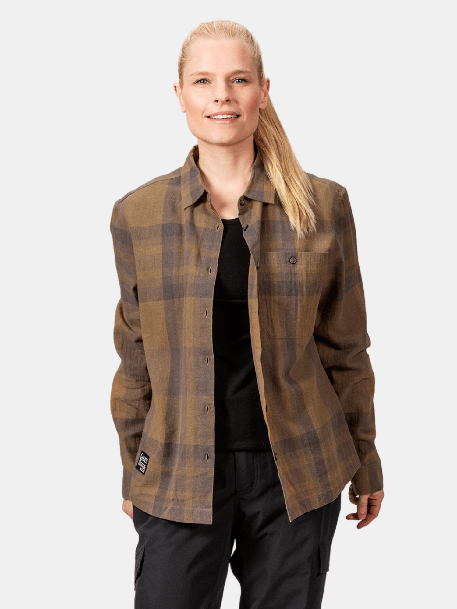 Eine Frau trägt das Halti Hiker Hemd Damen über schwarzem Top und Hose vor hellem Hintergrund.