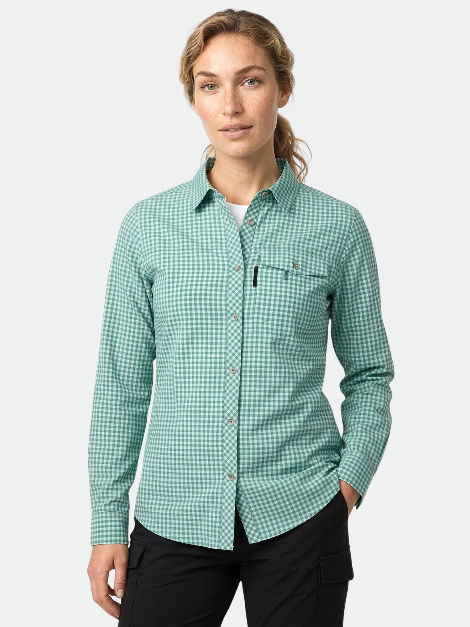 Eine Frau trägt die Halti Kota Outdoor Bluse Damen in grünem Karo, hergestellt aus Active Dry Stoff, Hand in der Tasche.