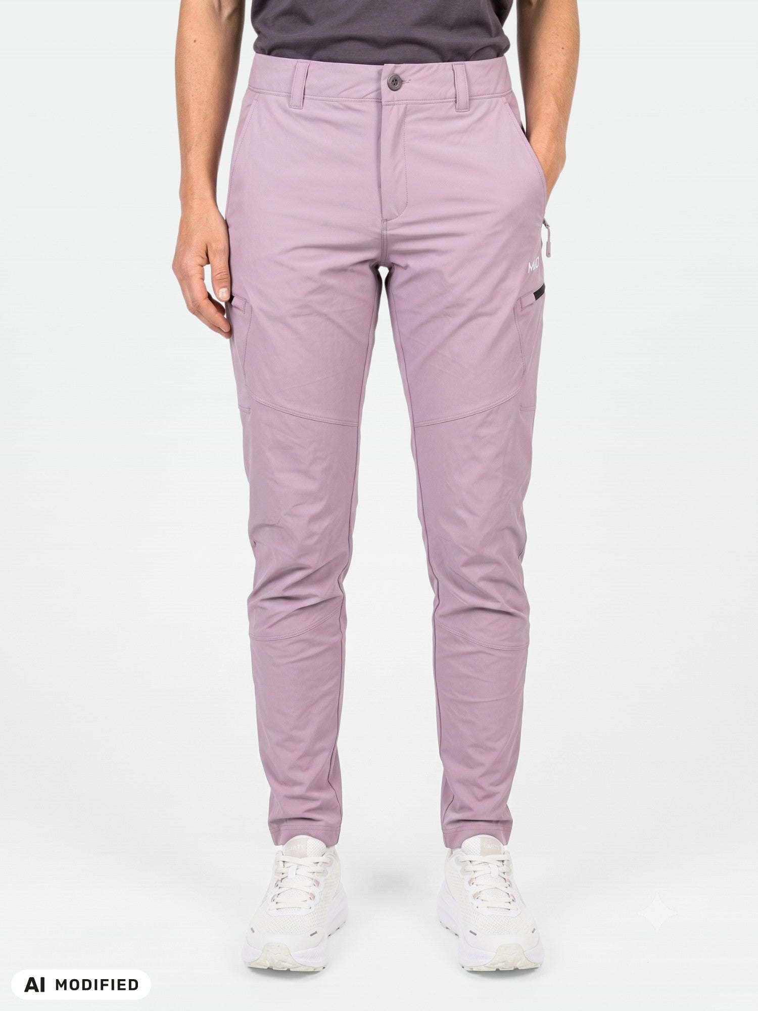 Eine Person, die hellviolette „Halti Pallas Evo X-Stretch“-Hosen für Damen und weiße Sneaker trägt, vor einem einfarbigen Hintergrund.
