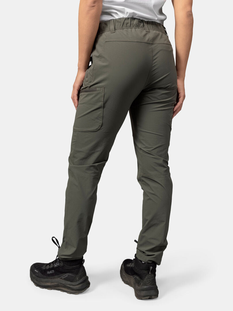 Eine Person in olivgrünen Halti Pallas Evo X-Stretch-Hosen Damen und schwarzen Wanderschuhen, von hinten gesehen.