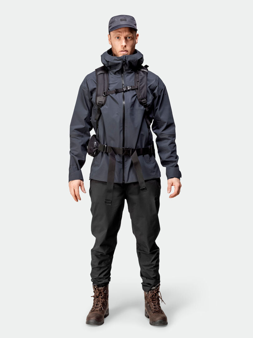 In der Halti Kajana 3L DX Regenjacke Herren, den Stiefeln, der Mütze und dem Rucksack blickt man nach vorne – perfekt für Outdoor-Fans.