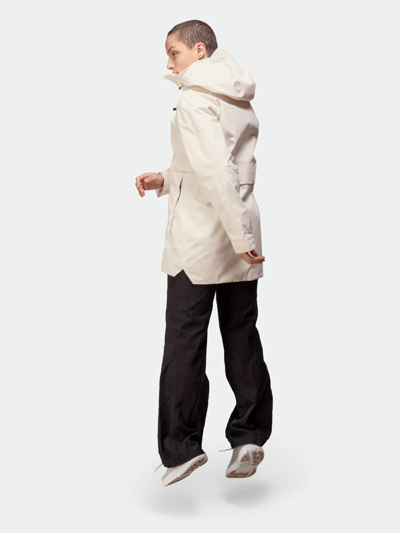 Jemand in der Halti Kallas DX Parka Jacke Damen und dunklen Hosen springt und blickt von der Kamera weg.