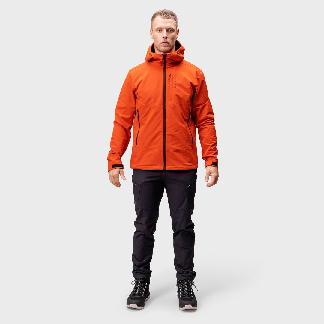 Eine Person blickt nach vorne und trägt eine Halti Pallas Evo Brushed X-Stretch-Jacke für Herren, schwarze Hosen und Wanderstiefel.