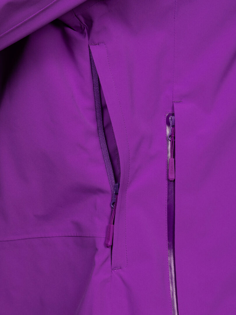 Nahaufnahme der Halti Staala DX Regenjacke für Damen in Lila, mit Reißverschlusstasche, Nahtdetails und wasserabweisendem Material.