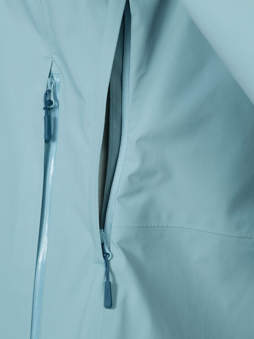 Nahaufnahme der Halti Staala DX Regenjacke Damen Plus in hellblau, mit zwei teilweise offenen Reißverschlusstaschen.