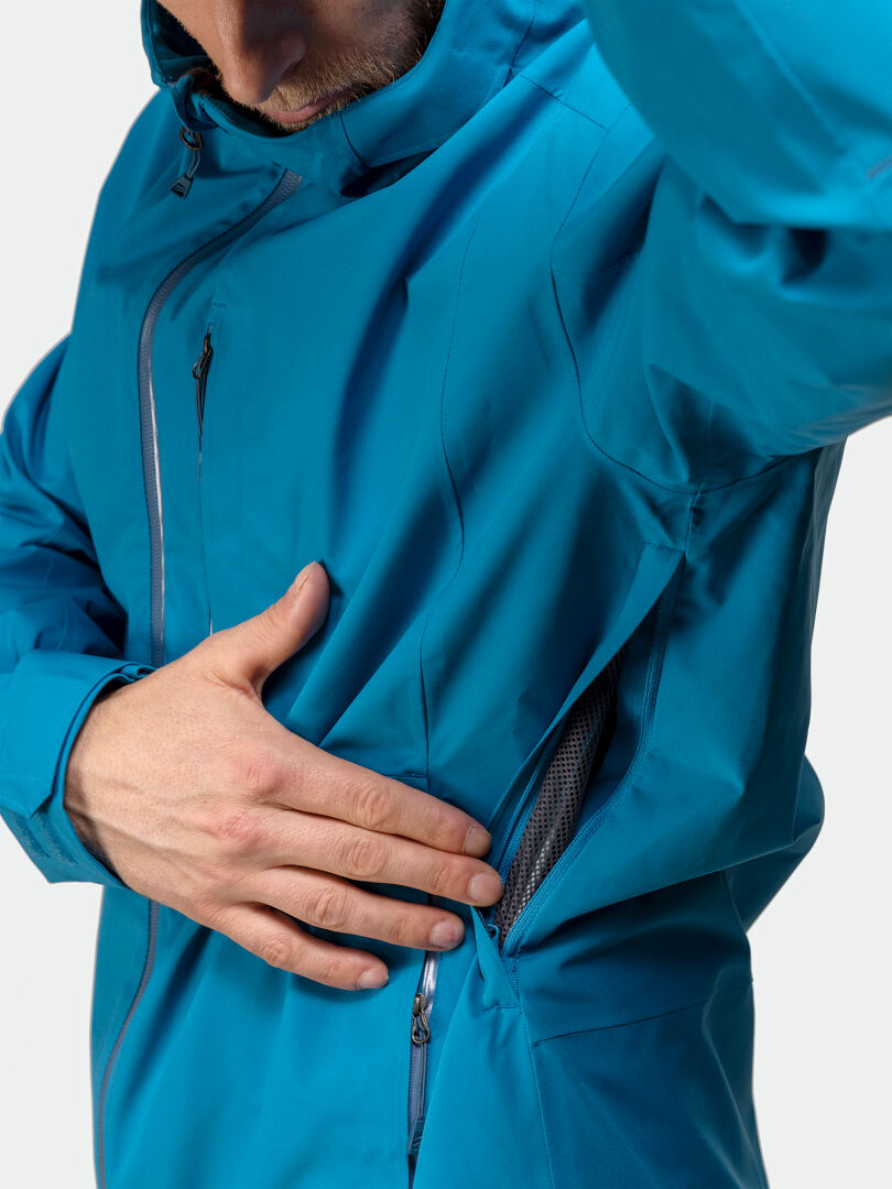 Ein Mann in einer Halti Staala DX Regenjacke öffnet den Reißverschluss eines Schlitzes und gibt das Netz frei - ideal für Outdoor-Abenteuer.