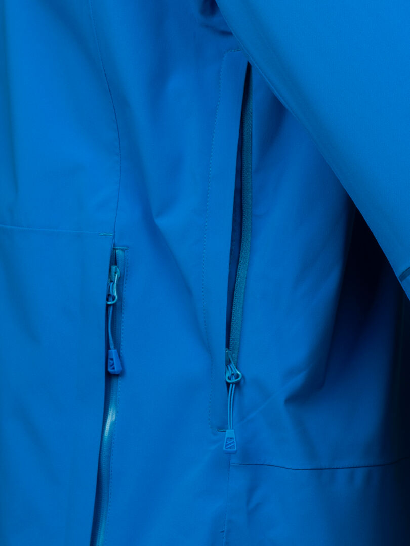 Nahaufnahme der Halti Staala DX Regenjacke Herren, einer blauen Regenjacke mit zwei Reißverschlusstaschen und passenden Pullern.