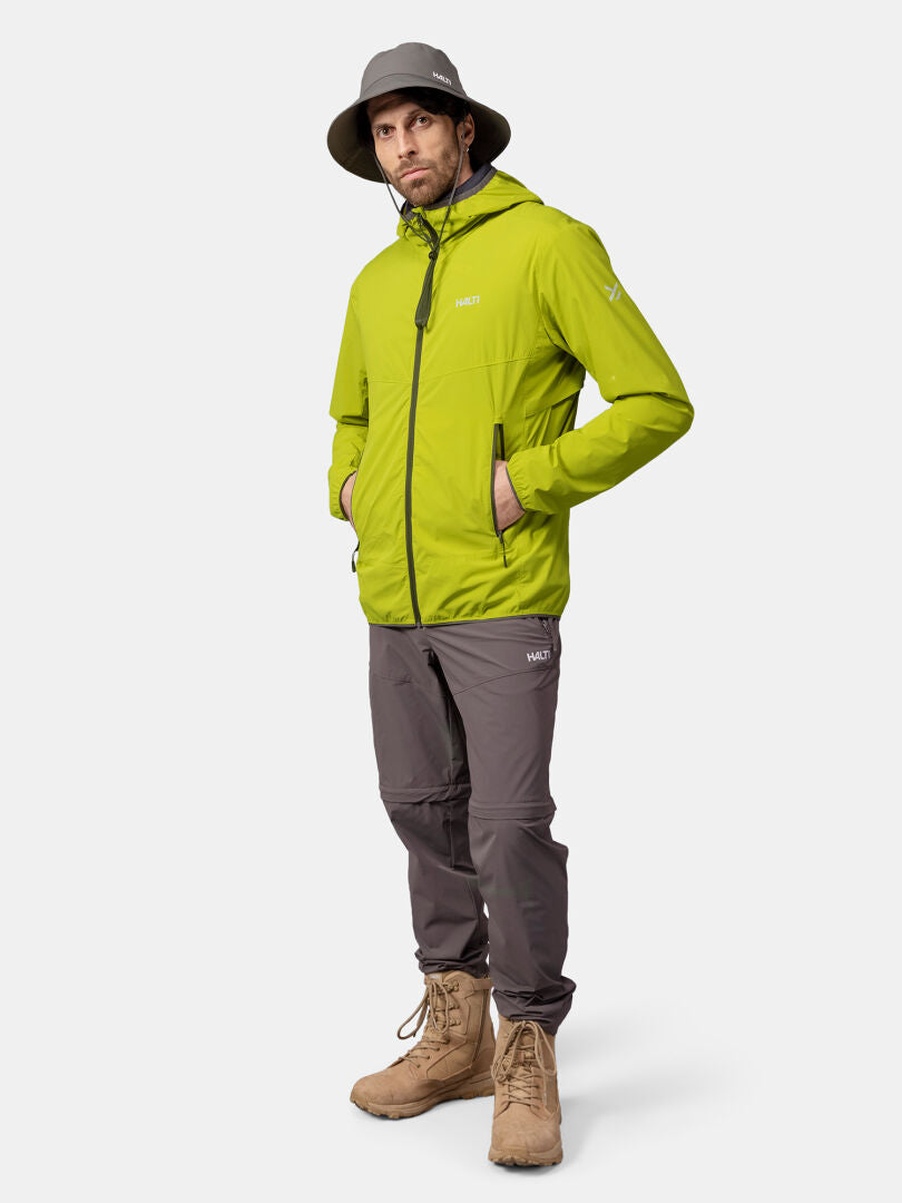 Ein Mann trägt eine grüne Halti Pallas Cool X-stretch Herrenjacke, eine graue Hose, braune Stiefel und einen breitkrempigen Hut.