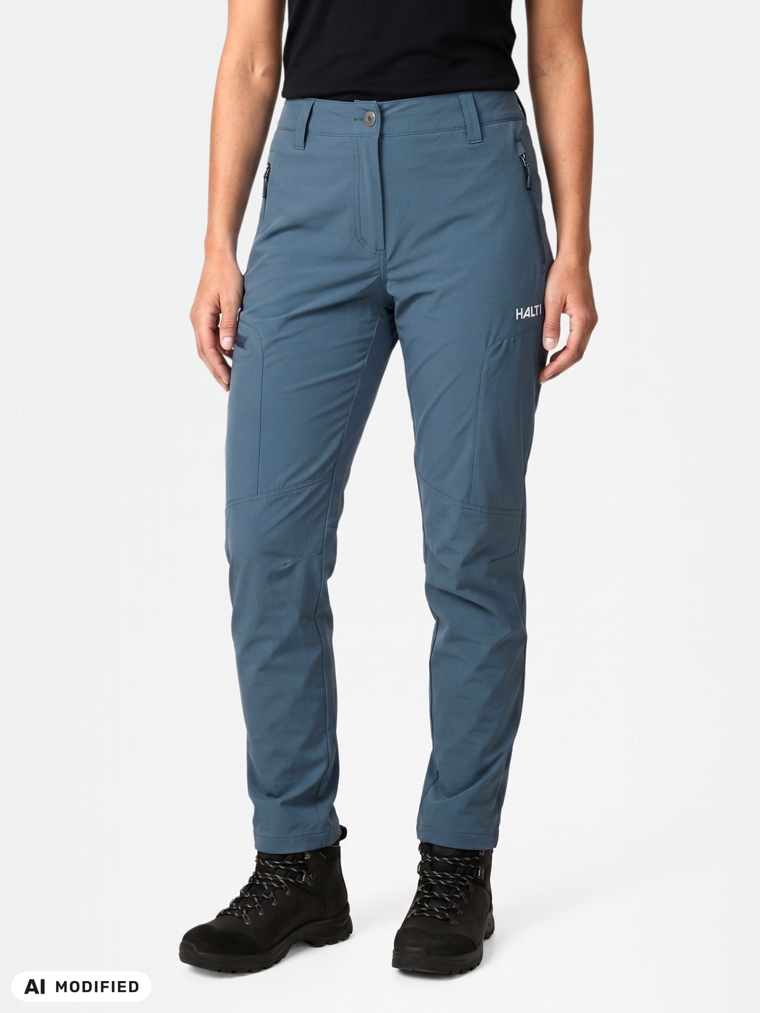 Frau in einer Halti Pallas Cool X-Stretch-Hose und schwarzen Stiefeln vor weißem Hintergrund.