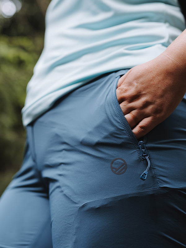 Frau trägt Halti Pallas Cool X-Stretch Caprihose Damen Plus mit LSF 90+, Hand in der Tasche im Freien.