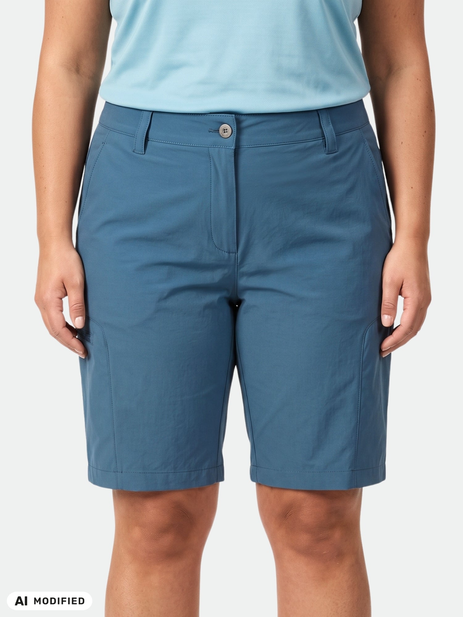 Eine Frau in „Halti Pallas Cool Shorts Damen Plus“ und einem hellblauen Shirt, die mit nach vorne gerichtetem Blick und an den Seiten hängenden Armen dasteht.