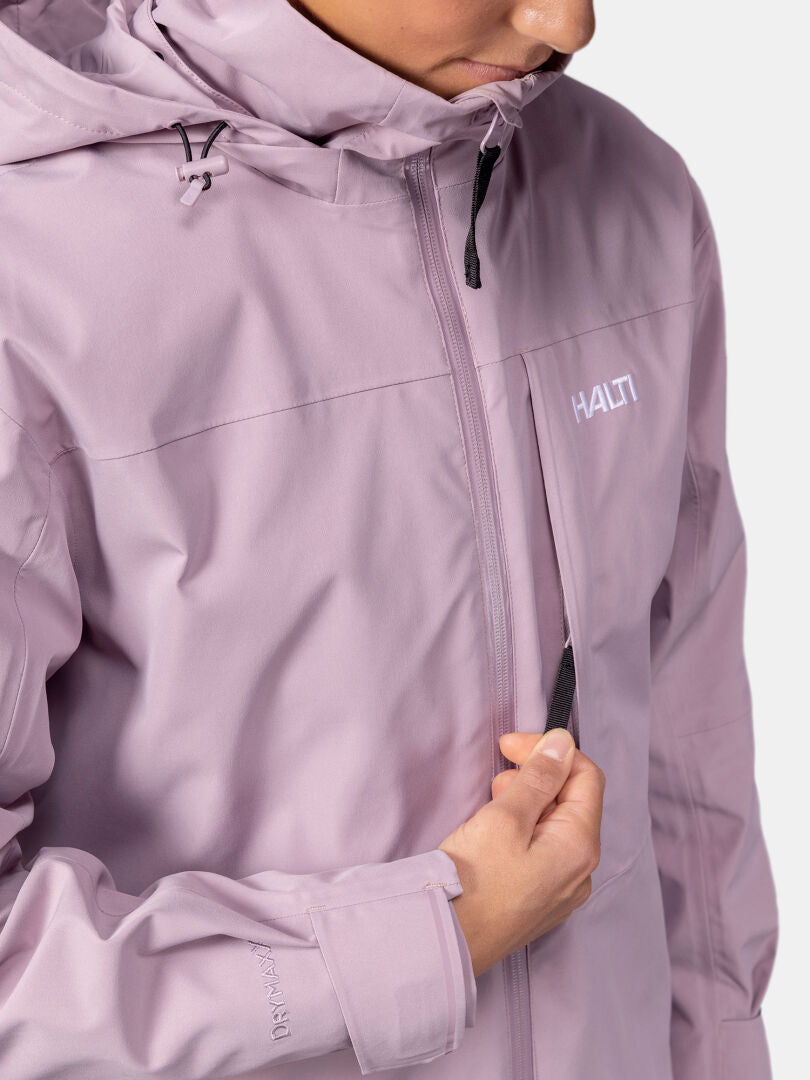 Frau in einer hellvioletten Halti Valaja DX Parkajacke öffnet die Brusttasche; nur ihr Untergesicht und ihr Oberkörper sind zu sehen.