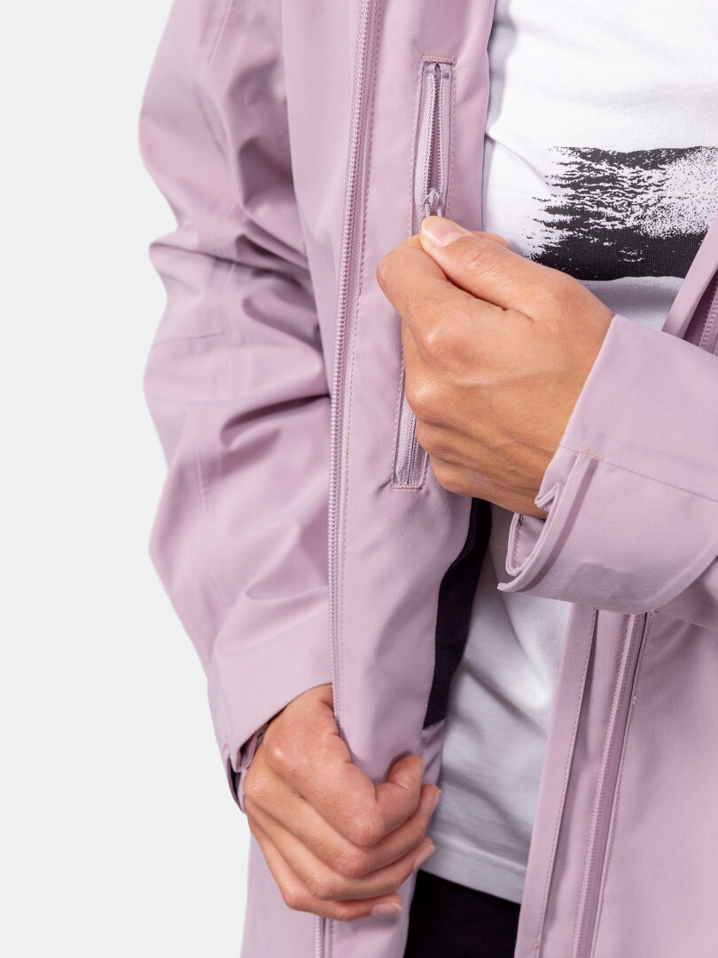 Jemand in einem hellvioletten Halti Valaja DX Parkajacke Damen öffnet die Brusttasche und gibt den Blick auf ein weißes Hemd darunter frei.