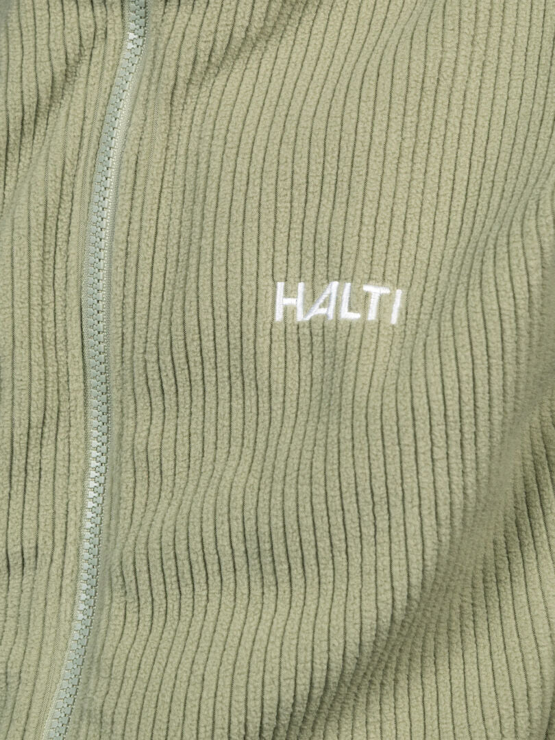 Nahaufnahme der Halti Loito 3-in-1 DX Damenjacke aus hellgrünem Rippstrick mit Reißverschluss und gesticktem Logo auf der Brust.