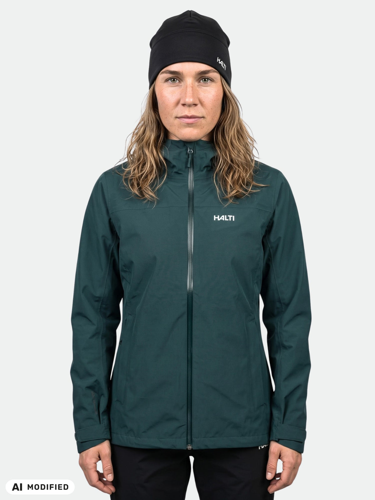 Eine Person trägt eine dunkelgrüne, wasserdichte Kaltimo DX Regenjacke Damen mit Reißverschluss und eine schwarze Mütze.