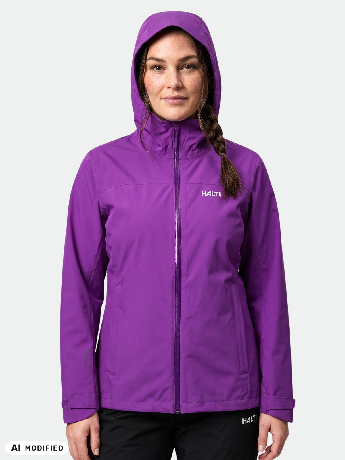 Eine Person in einer violetten Halti Kaltimo DX Regenjacke Damen Plus mit hochgezogener Kapuze, die vor einem weißen Hintergrund steht.