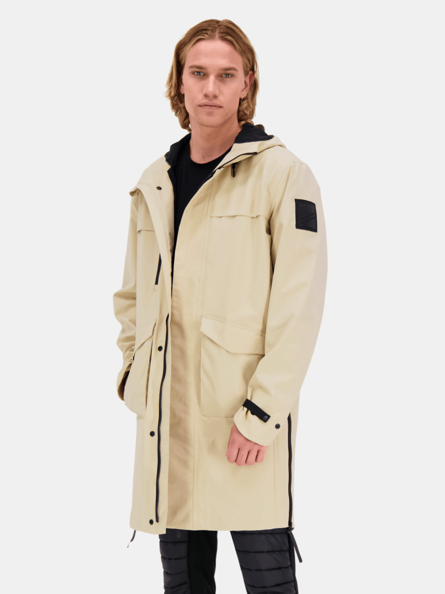 Eine Person trägt eine Halti Tokoi Herren DrymaxX Parka Jacke über schwarzer Kleidung vor einem weißen Hintergrund.