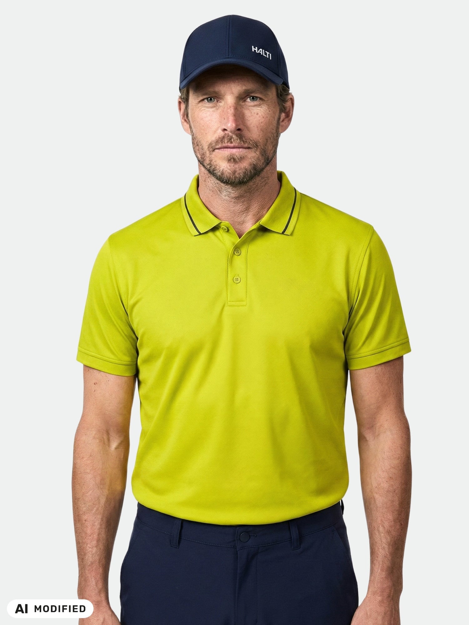Ein Mann in einem „Halti Laine Technisches Poloshirt Herren“ und einer marineblauen Mütze steht vor einem schlichten, hellen Hintergrund.