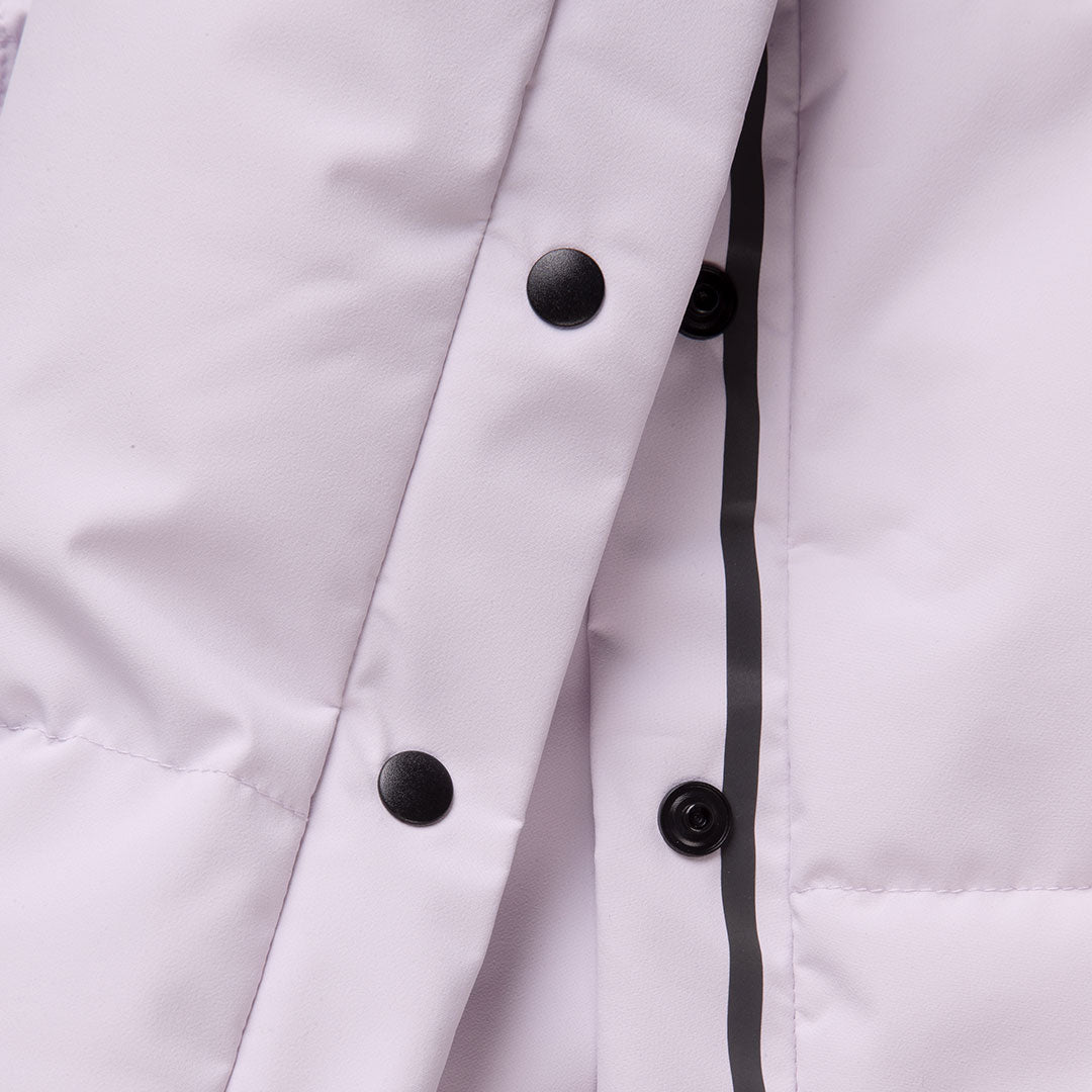 Nahaufnahme einer hellen Halti Penger Winterjacke für Damen mit schwarzen Druckknöpfen und einem vertikalen schwarzen Besatz entlang der Naht.