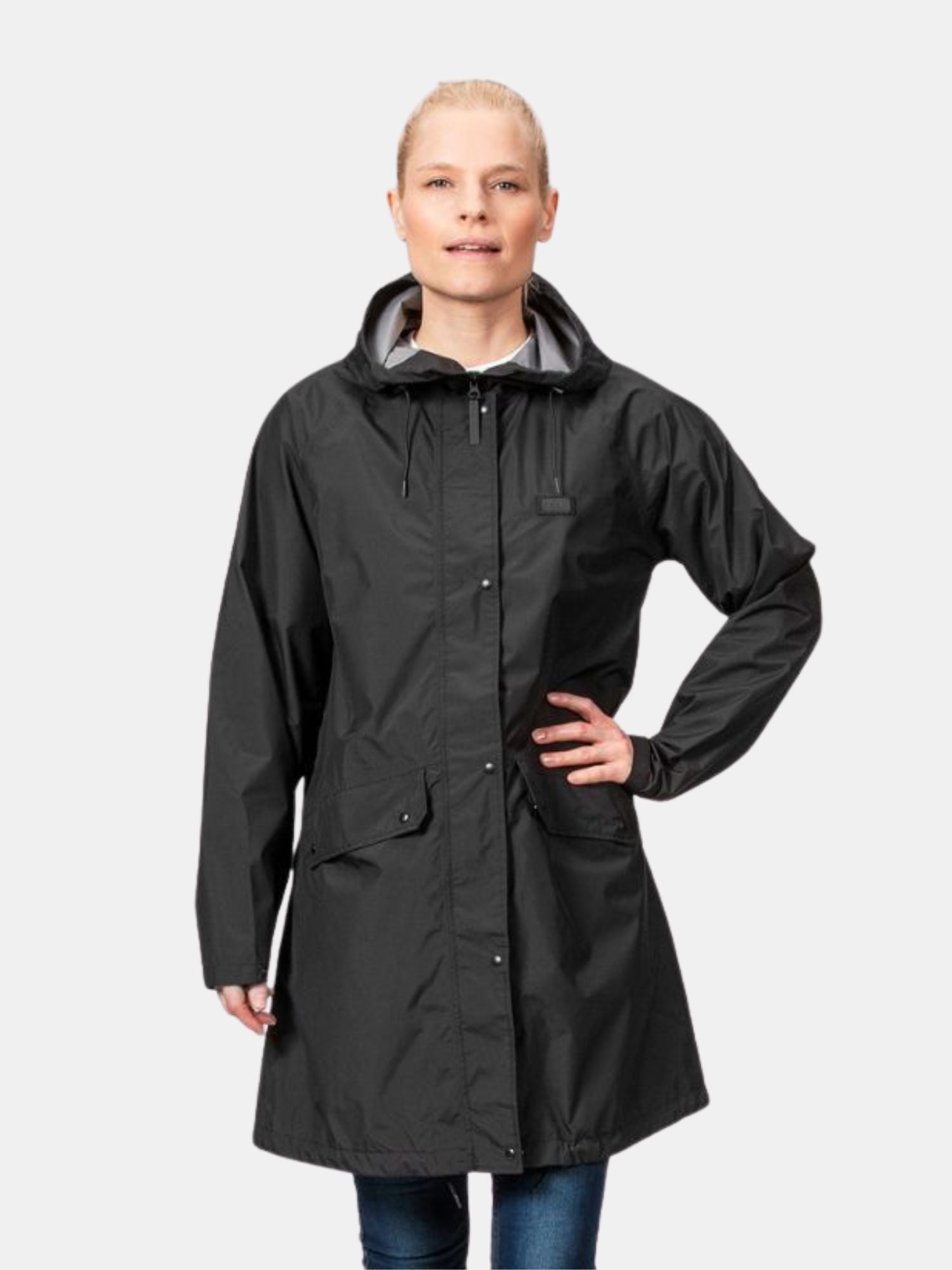 Eine Person in der Halti Kevee Parka Jacke Damen, einem leichten, atmungsaktiven Parka, steht vor einem schlichten Hintergrund.