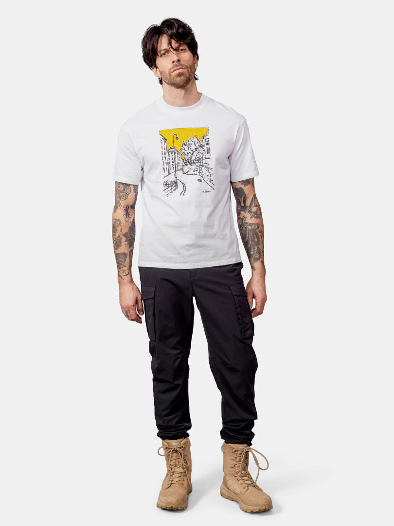 Mann, der ein Halti Skaltsi Unisex T-Shirt, eine schwarze Hose und hellbraune Stiefel trägt.