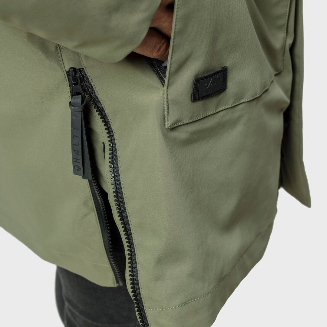 Nahaufnahme einer Person, die den Halti Synkas 3in1 DrymaxX Parka Herren in Helloliv mit sichtbarem Reißverschluss und Microtherm®-Patch trägt.