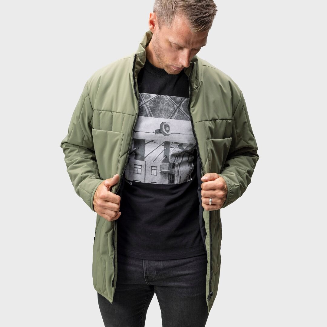 Mann trägt einen Halti Synkas 3in1 DrymaxX Parka für Herren über einem schwarzen T-Shirt mit Grafik, blickt nach unten und hält es offen.