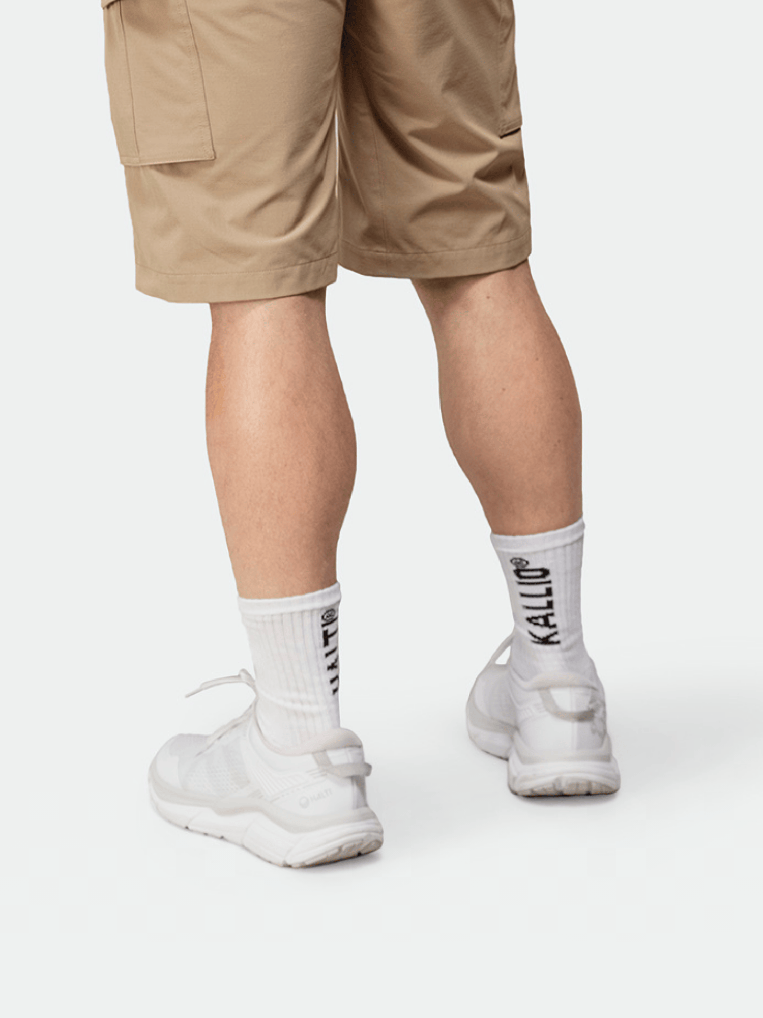 Person in hellbraunen Shorts, weißen Turnschuhen und Halti Kallio Socken, die einen zeitlosen Sportstil verkörpert.