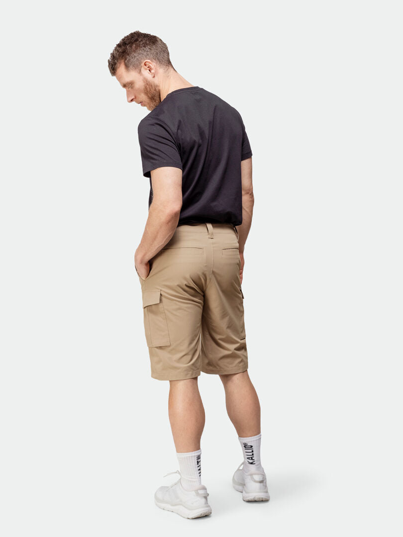Ein Mann in Halti Roams Shorts für Herren, schwarzem T-Shirt, weißen Socken und weißen Turnschuhen blickt abgewandt.