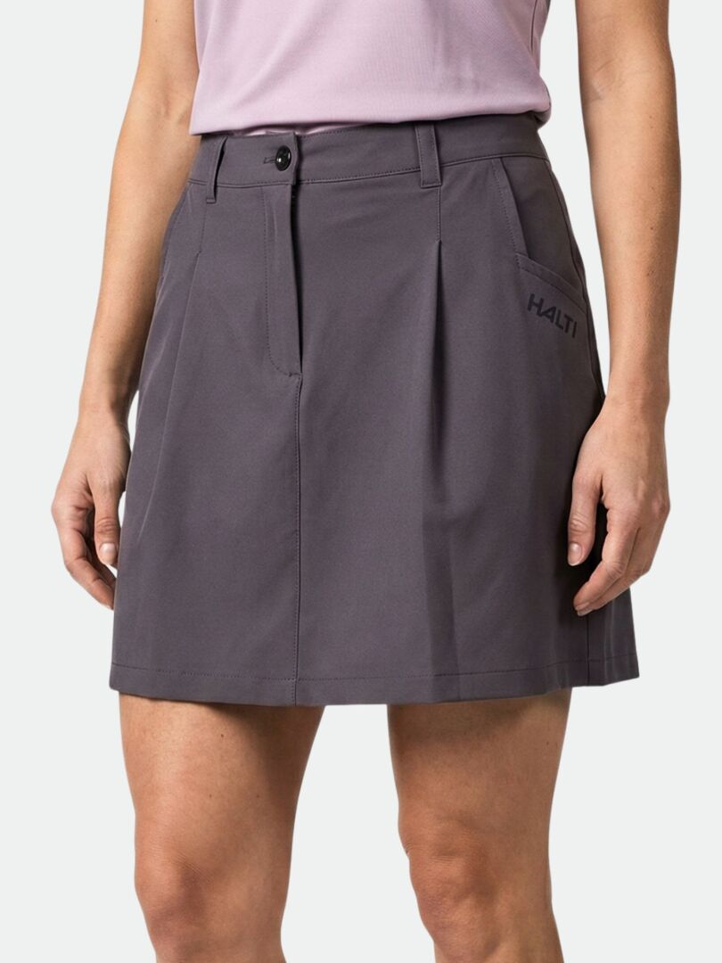 Eine Person trägt einen dunkelgrauen Halti Drive X-stretch Skort Damen mit Taschen und einem geknöpften Bund, gepaart mit einem hellvioletten Oberteil.