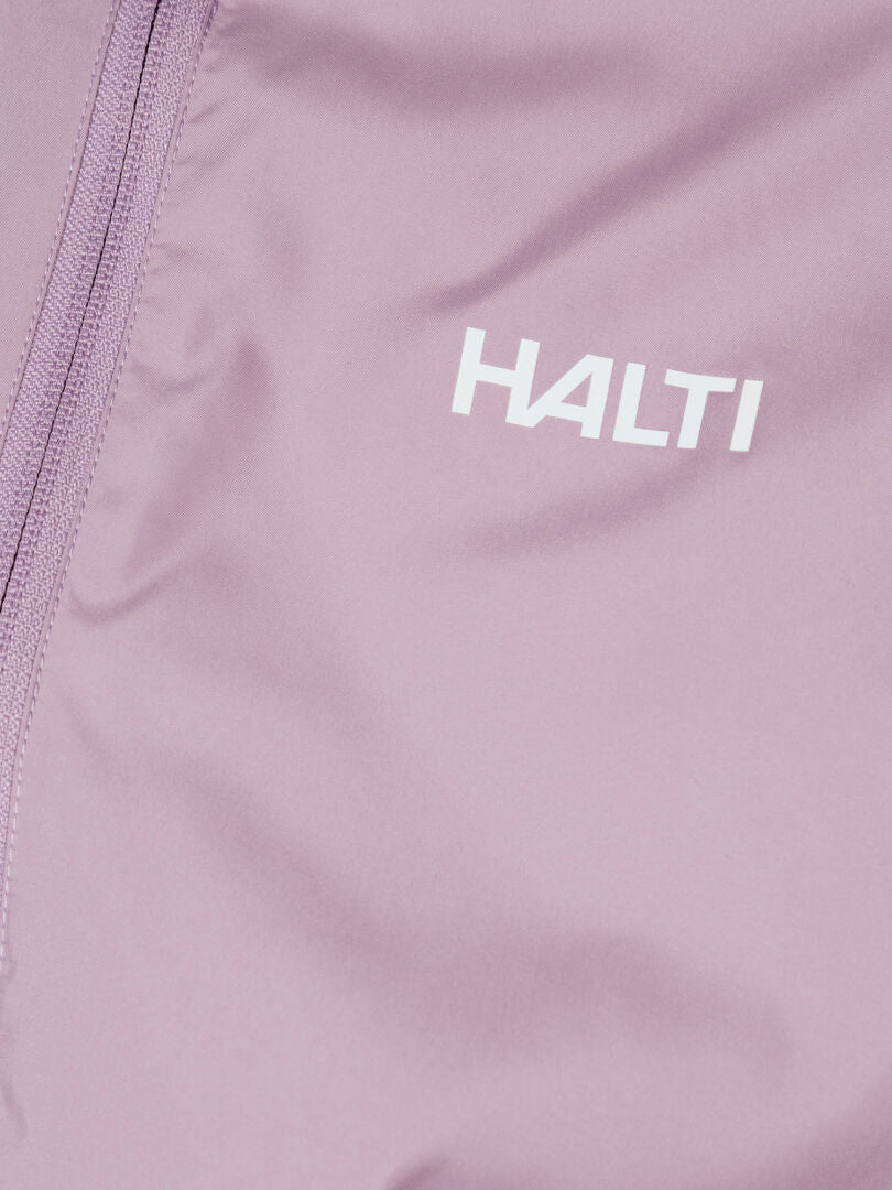 Nahaufnahme von Halti Saime Windbreaker Jacke Damen in helllila mit Reißverschluss, weißes Logo, aus recycelten Materialien.