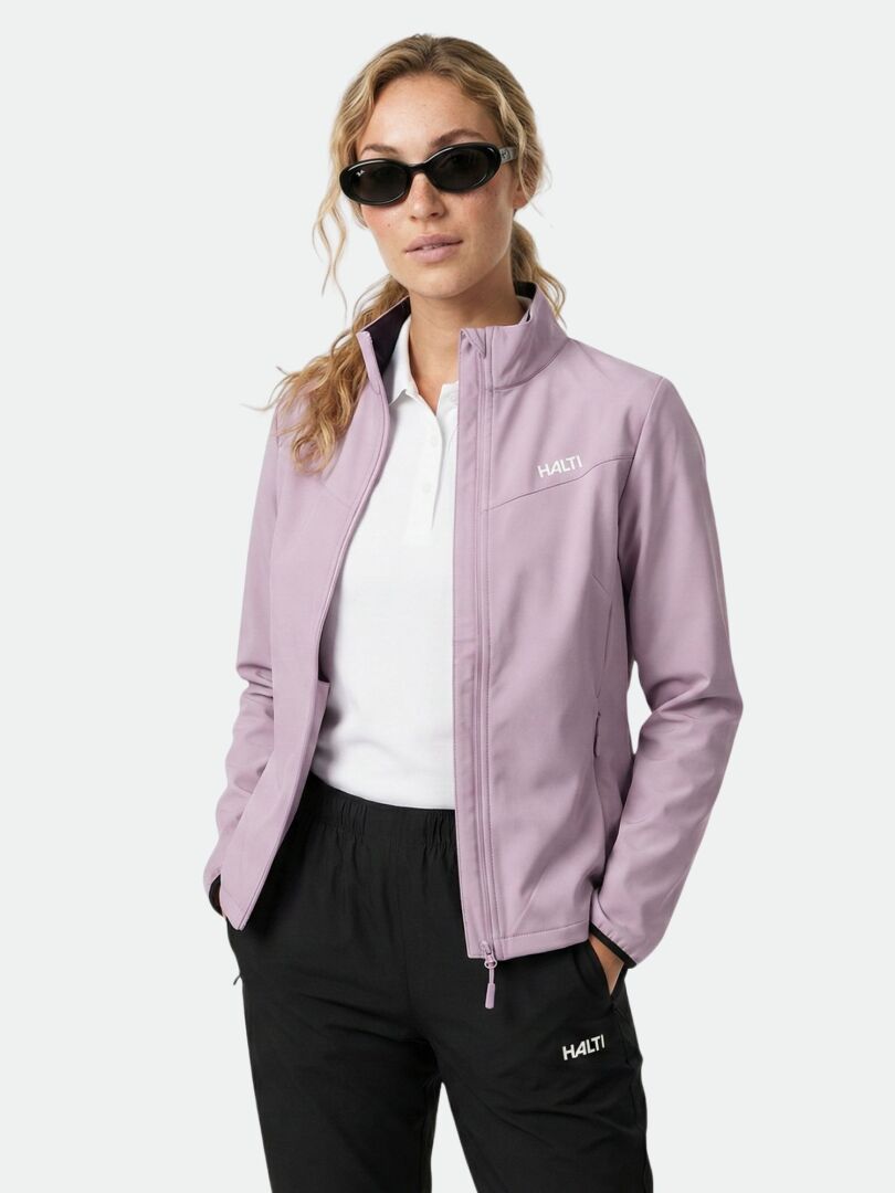 Eine Frau in der Halti Wedge Softshell Jacke Damen aus recycelten Materialien steht mit den Händen in den Taschen.