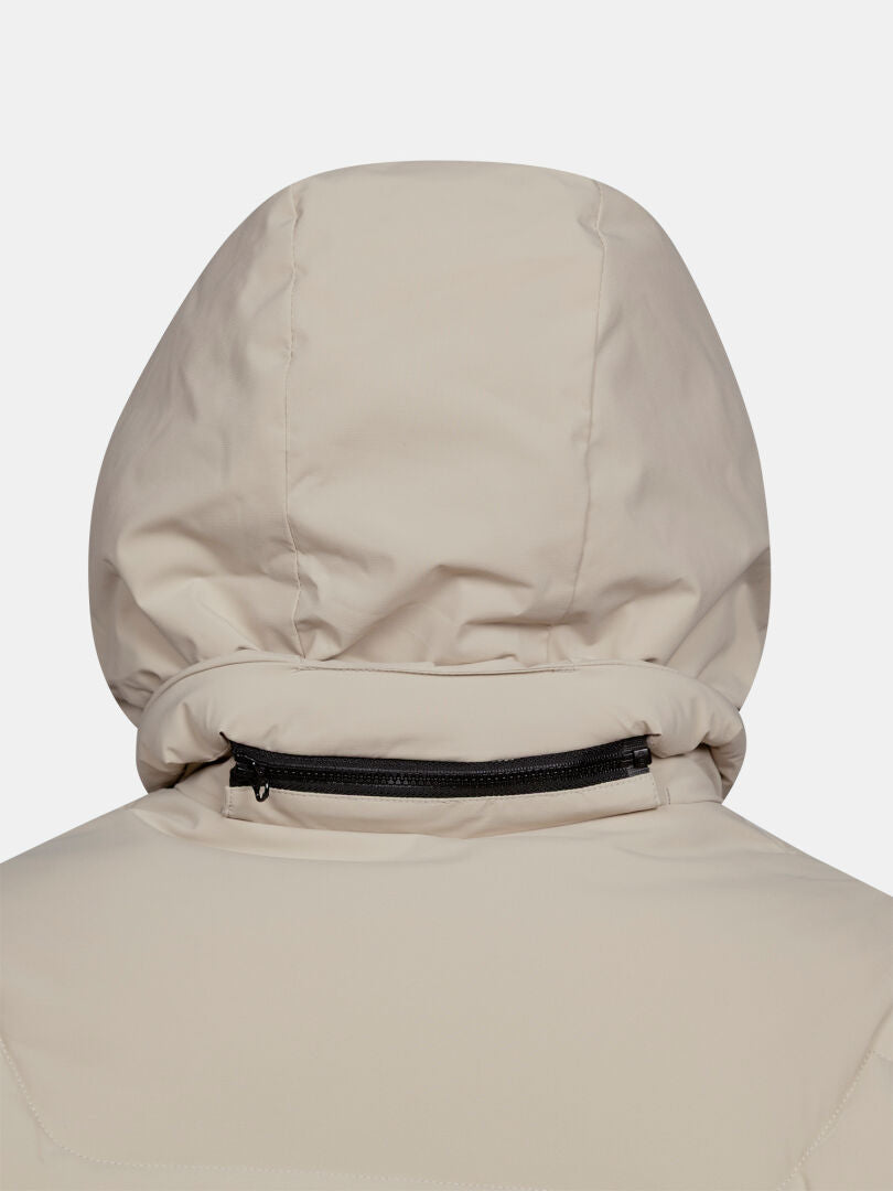 Nahaufnahme der Rückseite der „Brahe Puffer Long Winterjacke Damen“ von Halti in Beige, mit doppelter Isolierung und schwarzem Reißverschluss.